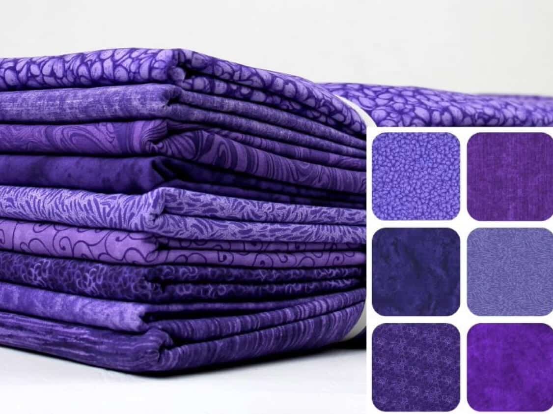 Stack of coordinating purple fat quarters showing nine different tonal and floral quilting cotton prints.