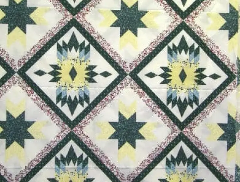 A geometric patchwork quilt pattern featuring Lone Star blocks set on point in dark green, yellow, blue, and white with a burgundy speckled sashing